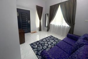 a living room with a purple couch and a window at Homestay Babah in Jitra