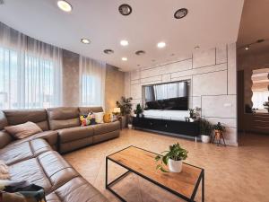 ein Wohnzimmer mit Sofa und großem Fernseher in der Unterkunft וילת אתרוג - וילה וצימר מושלמים עם בריכה באשלים in Ashalim