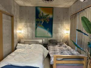 a bedroom with two twin beds and a painting on the wall at オランウータンApple House Ginowan in Ginowan