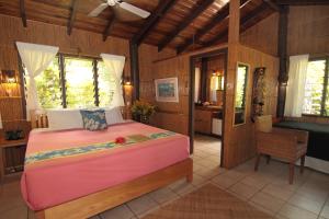 a bedroom with a large bed and a bathroom at Coconut Grove Beachfront Cottages in Matei