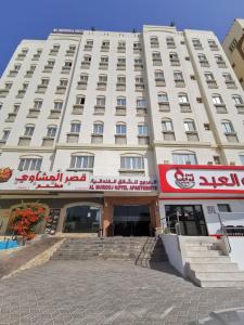 a large white building with a sign on it at Al Murooj Hotel Apartments in Muscat