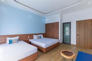 a bedroom with two beds and a table at Cocohamlet Villa in Thanh Ðông (1)