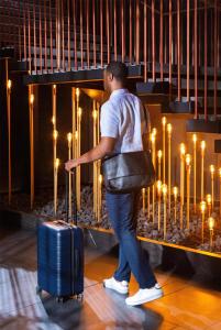 a man walking with a suitcase in front of candles at Thompson San Antonio - Riverwalk, by Hyatt in San Antonio +99 photos