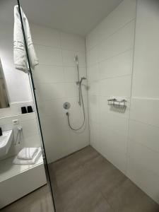 a white bathroom with a shower and a sink at SeePERLE 131 in Friedrichshafen +13 photos