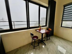 a table and two chairs in a room with windows at Lùma Sapa Homestay in Sapa