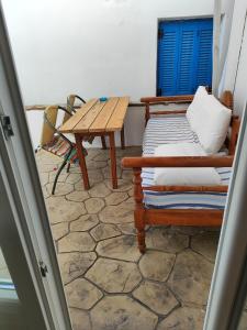 a room with a table and a bench and a table and blue shutter at Four Seasons Rooms & Apartments in Ios Chora