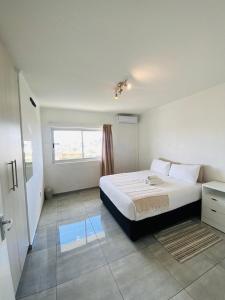 ein weißes Schlafzimmer mit einem Bett und einem Fenster in der Unterkunft City Duplex Trift Towers Apartment in Windhoek