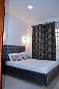 a bedroom with a bed with a headboard and a curtain at Kivuli suites in Eldoret
