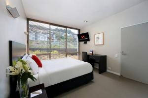 a bedroom with a white bed and a window at Swiss-Belsuites Pounamu Queenstown in Queenstown