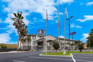 a building with two flags in a parking lot at Sleep Inn & Suites Valdosta Mall Area in Valdosta