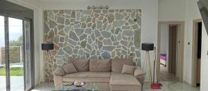 a living room with a couch and a stone wall at villa kate view in Ratzaklíon