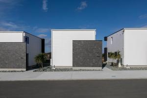 three buildings with palm trees in front of a street at Seven Saunas Village in Arao