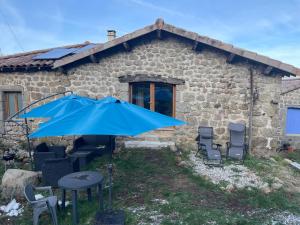 a blue umbrella in front of a stone house at Gîte des Nicolaux in Beauvène