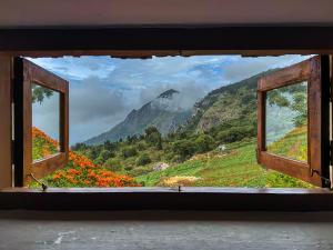an open window with a view of a mountain at Hullathy by Red Earth in Ooty
