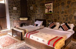 two beds in a room with a fireplace at Hullathy by Red Earth in Ooty