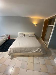 a bedroom with a white bed and a tiled floor at Les Bruyères in Martigues