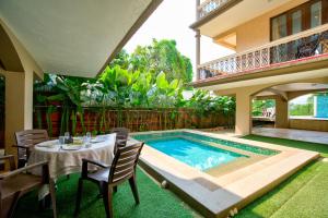 a patio with a table and chairs next to a swimming pool at Aveeno Resort with Swimming Pool and Jacuzzi Near Calangute and Baga in Sangolda