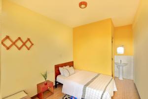 a bedroom with yellow walls and a bed and a sink at Budget Gest House in Lalibela +1 photo
