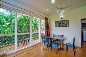 a dining room with a table and chairs and large windows at Aveeno Resort with Swimming Pool and Jacuzzi Near Calangute and Baga in Sangolda