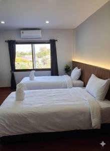two beds in a hotel room with a window at Ma Relax Place in Ban Nong Chaeng