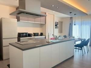 a kitchen with white cabinets and a counter top at Akikawa Toshima 2 プレミアム鉄骨 一棟貸切ヴィラ in Kumamoto