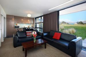 a living room with two black leather couches and a table at Swiss-Belsuites Pounamu Queenstown in Queenstown