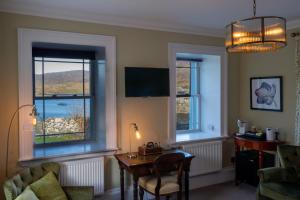 a living room with a table and two windows at Two Harbours Guest House in Scalpay