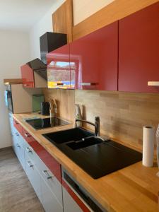 a kitchen with a sink and red cabinets at Wohnung Nähe Steyr bis 9 Personen in Ramingdorf