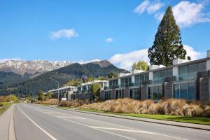 an empty road in front of a building with a tree at Swiss-Belsuites Pounamu Queenstown in Queenstown