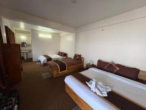 a hotel room with two beds and a bathroom at Delohighs in Kalimpong