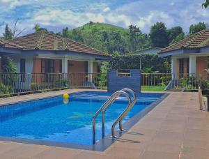 a swimming pool in front of a house at Misty Grove Resort in Devāla