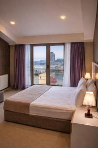a bedroom with a large bed with a large window at Diplomat Suites Hotel in Baku