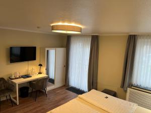 a hotel room with a bed and a desk and a television at Haus am Meer Steinhude in Steinhude