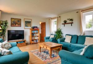 a living room with blue couches and a coffee table at Cricketers cottage in Tirley