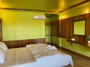 a bedroom with a large bed with a yellow wall at Pan guest house Donkhone in Ban Donsôm