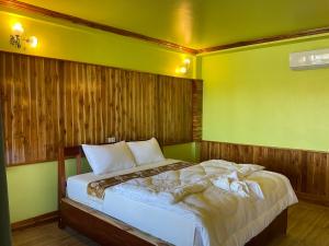 a bed in a room with a green wall at Pan guest house Donkhone in Ban Donsôm