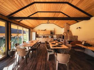 a dining room with tables and chairs and a kitchen at La Poalele Vulcanilor in Densuş
