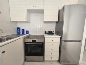 a kitchen with white cabinets and a stainless steel refrigerator at Beach Front View Apartment Sea Pool & Prime Location in Limassol