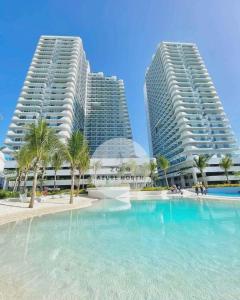 two tall buildings next to a swimming pool with palm trees at Z Crib - Azure North in San Fernando