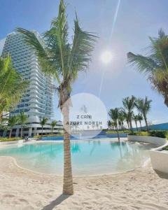 a palm tree on the beach in front of a hotel at Z Crib - Azure North in San Fernando