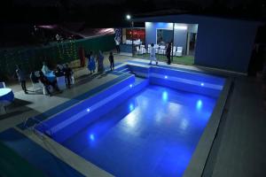 a swimming pool with blue lights in a building at Drop Hills Farm Noida in Noida +8 photos