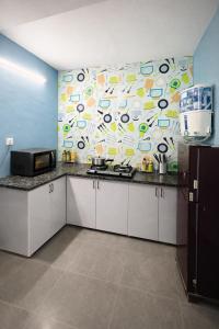 a kitchen with white cabinets and a colorful wall at Drop Hills Farm Noida in Noida