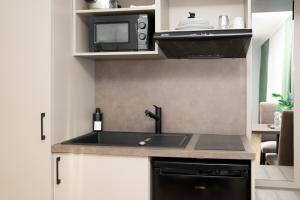 a kitchen with a sink and a microwave at Living Inn am Schlosspark - Zentral, Parkplatz und Kitchenette in Rheda-Wiedenbrück