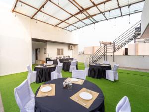 a room with tables and white chairs and green grass at Treebo Shridhar Stay, 2 km from Indore Junction in Indore
