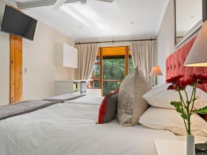 a large white bed in a room with a window at Pumula Lodge 4 Star Guesthouse Knysna in Knysna