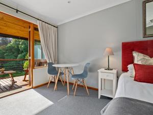 a bedroom with a bed and a table and chairs at Pumula Lodge 4 Star Guesthouse Knysna in Knysna