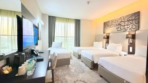 a hotel room with two beds and a flat screen tv at M Hotel Makkah by Millennium in Mecca