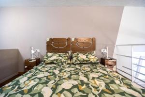 a bedroom with a bed with a green comforter at Casa degli Specchi- Duplex in Arona city center - By Guestaly in Arona