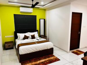 a bedroom with a large bed with a yellow wall at Nice Inn Residency in Kozhikode