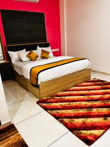 a bedroom with a large bed with a red wall at Nice Inn Residency in Kozhikode